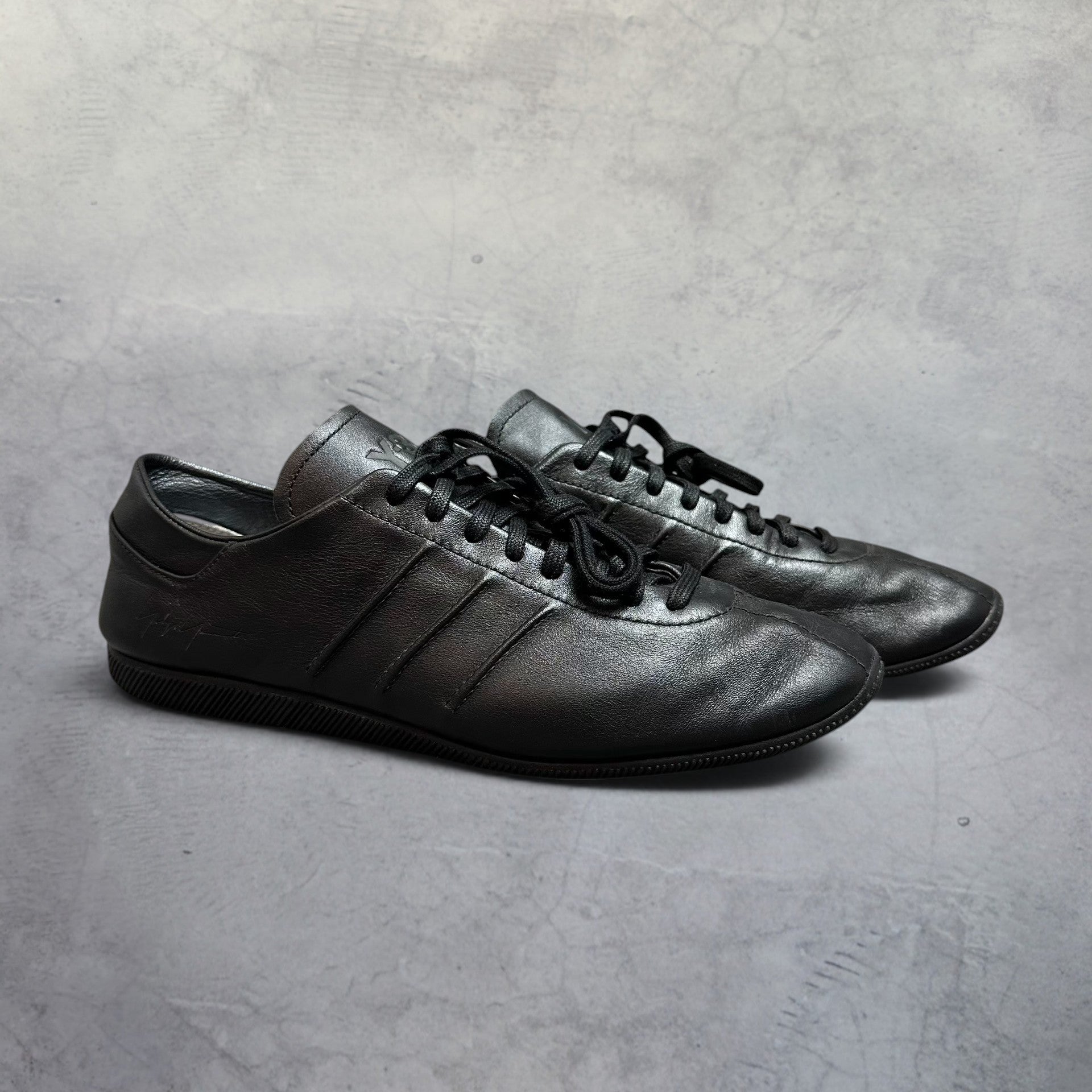 SĀN ARCHIVE GOODS Adidas Y-3 Japan triple black leather sneakers with tonal stitched stripes and low-profile rubber sole.